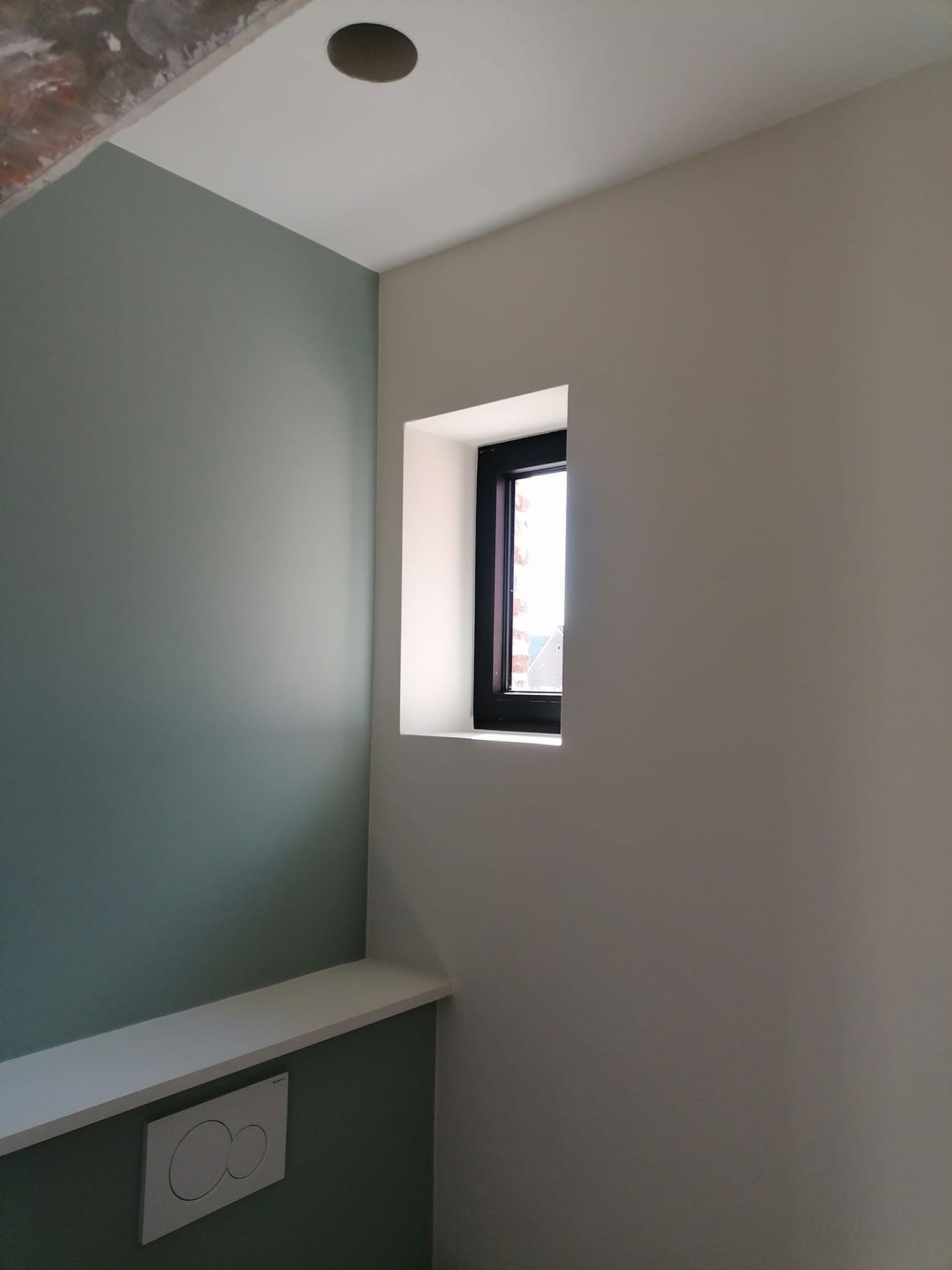 Slaapkamer met een groene accentmuur naast een zandkleurige wand