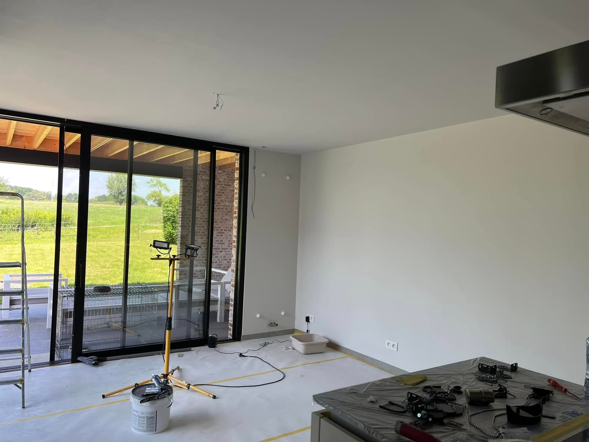 Nieuwe leefruimte met wit geschilderde muren en plafond en zwarte raampartij
