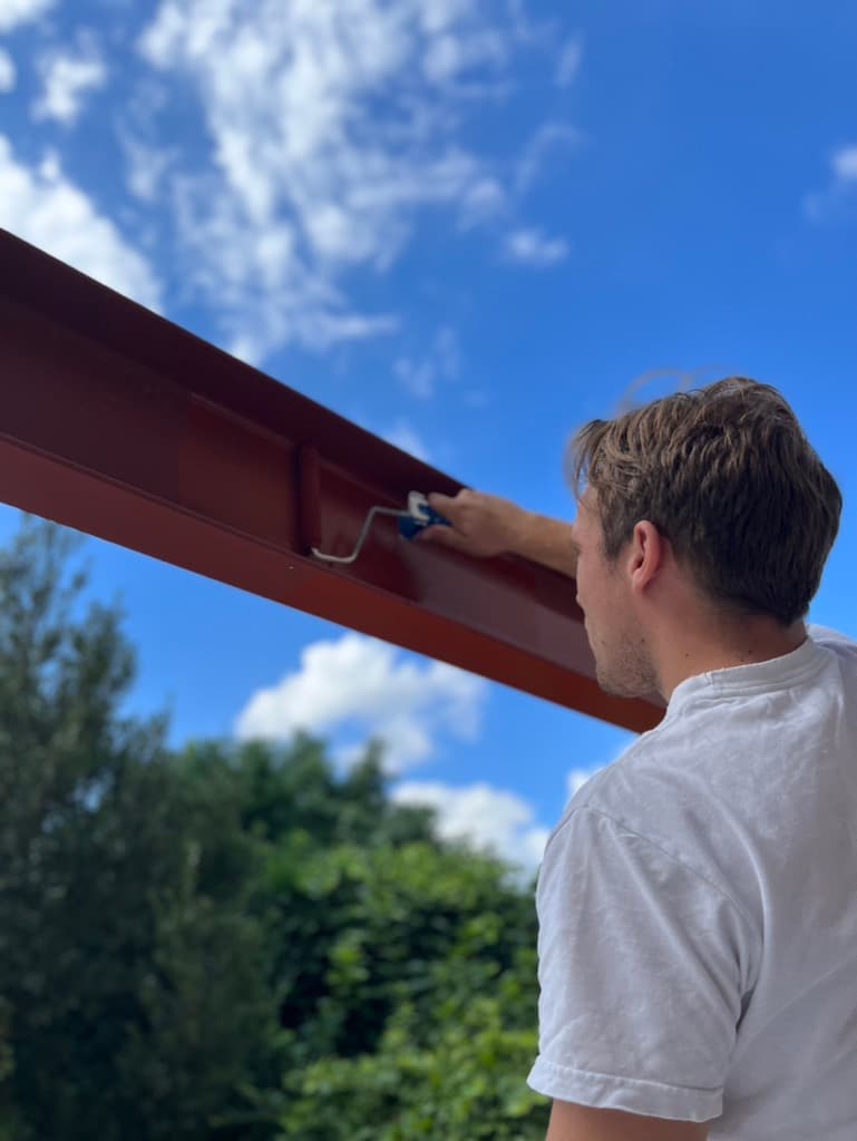 Vincent De Jonghe schildert het buitenschrijnwerk van een woning bij
